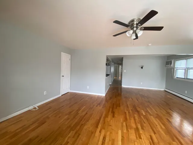 a view of a big room with wooden floor and windows