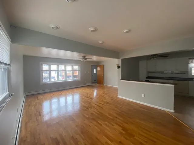 a view of an empty room with window and wooden floor