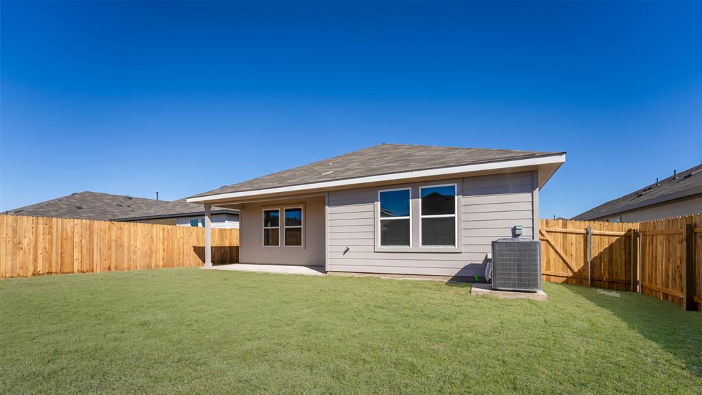 14021 Feinstein Street Manor, TX 78653 - Photo 25 of 25 A well-maintained yard and patio complement this charming home's private fenced backyard.