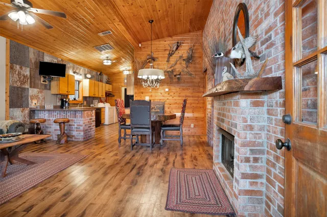 a kitchen with stainless steel appliances kitchen island granite countertop a table chairs in it and wooden floors