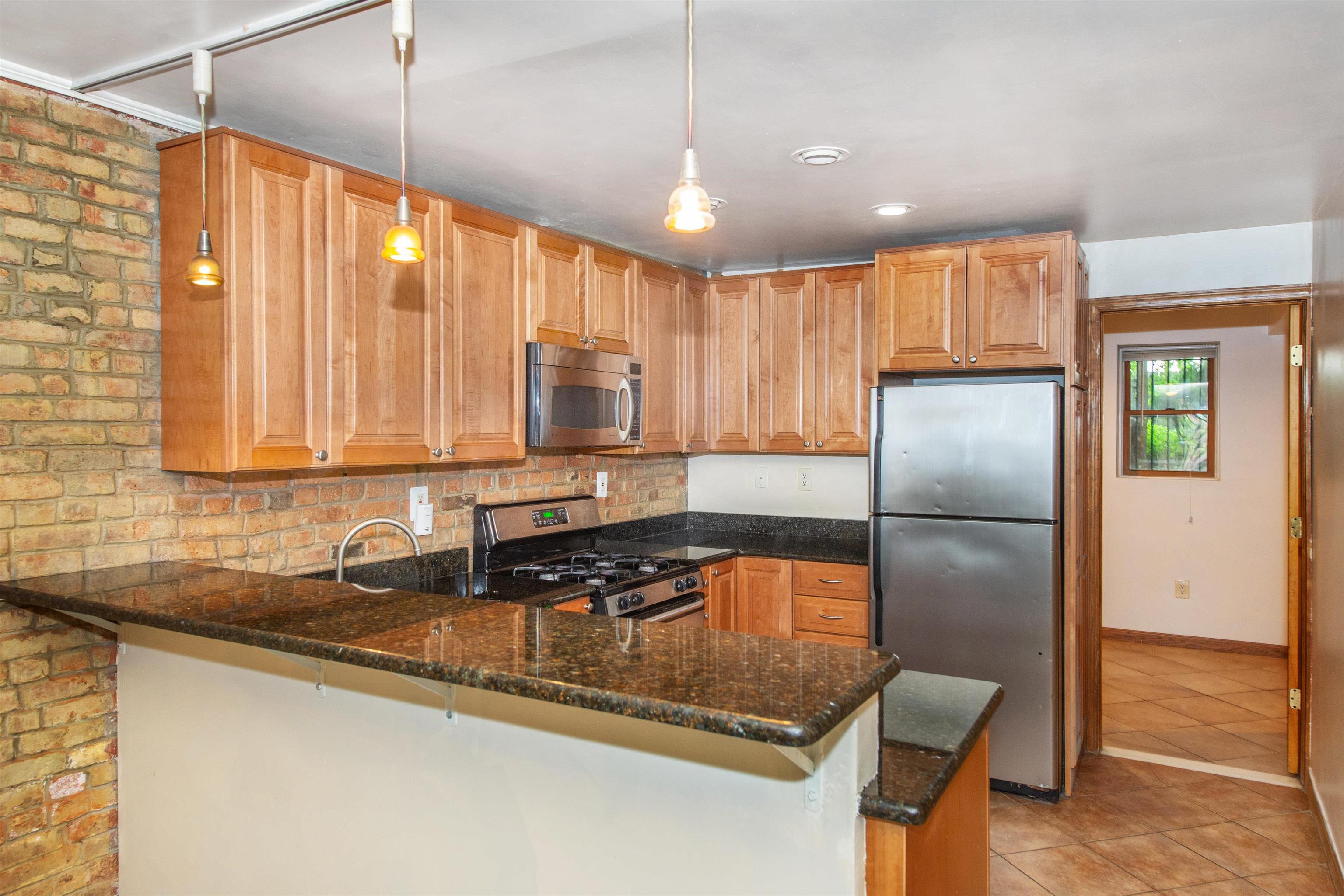 45 Monitor Street, Unit 1 Jersey City, NJ 07304 - Photo 7 of 14 a kitchen with kitchen island granite countertop a stove a refrigerator and a sink