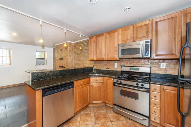a kitchen with granite countertop a sink cabinets and stainless steel appliances