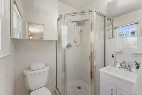 a bathroom with a shower a sink mirror and toilet