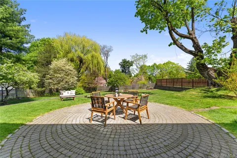 a view of a backyard with table and chairs potted plants and large tree