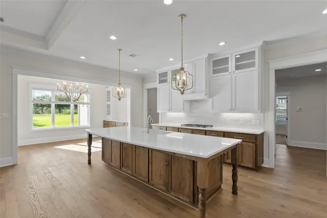 a large kitchen with kitchen island a stove a sink a center island and a wooden floor