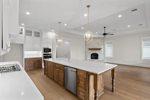 a large kitchen with kitchen island a stove a sink a oven and a fireplace with wooden floor