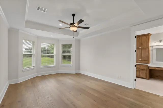 an empty room with wooden floor ceiling fan and window