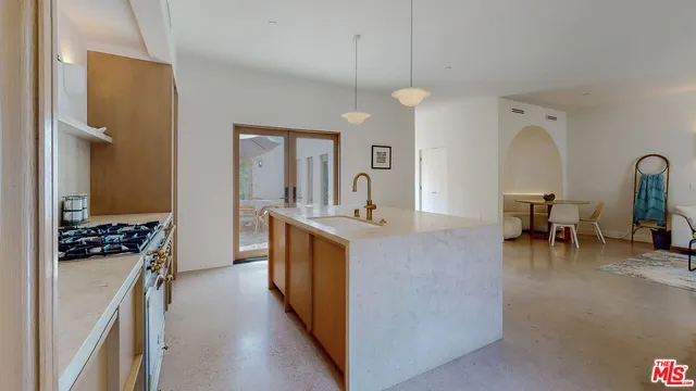 a large kitchen with kitchen island a large counter space a sink stainless steel appliances and cabinets