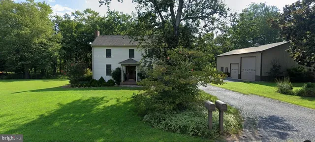 a front view of a house with garden and trees