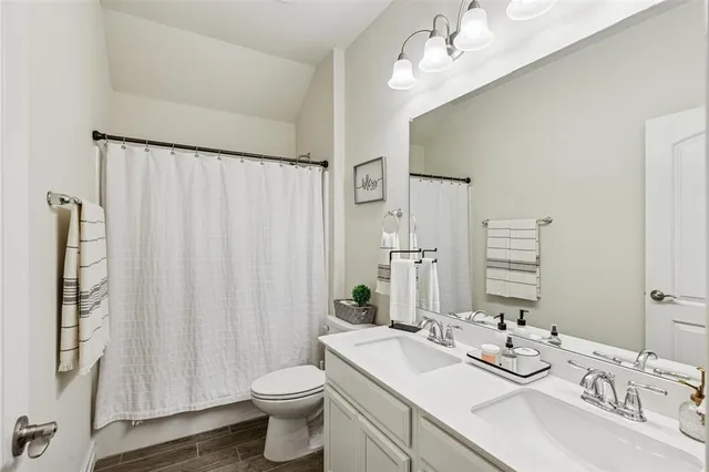a bathroom with a double vanity sink toilet and a mirror