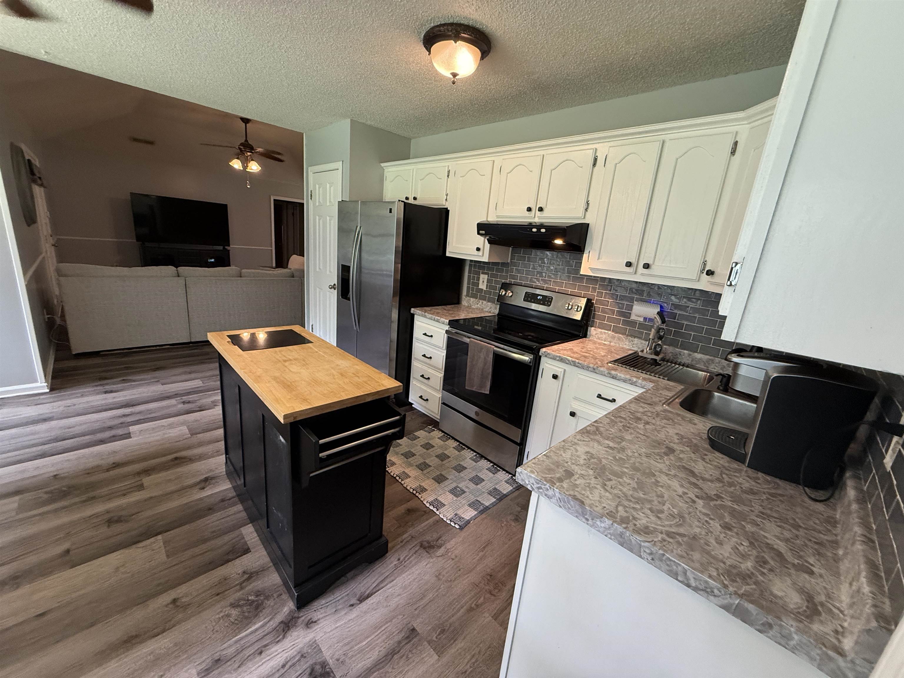 185 Mignon Road Atoka, TN 38004 - Photo 19 of 34 Kitchen featuring white cabinetry, gray tile backsplash, stainless steel appliances, and wood-finish flooring