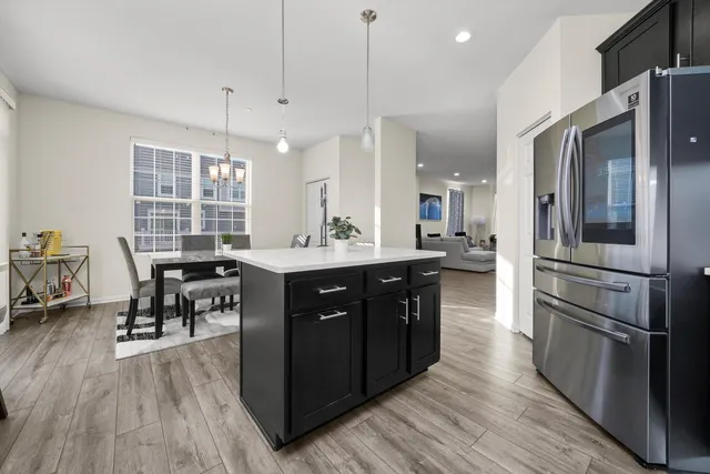 a kitchen with stainless steel appliances granite countertop a refrigerator a sink dishwasher a stove and white countertops with wooden floor