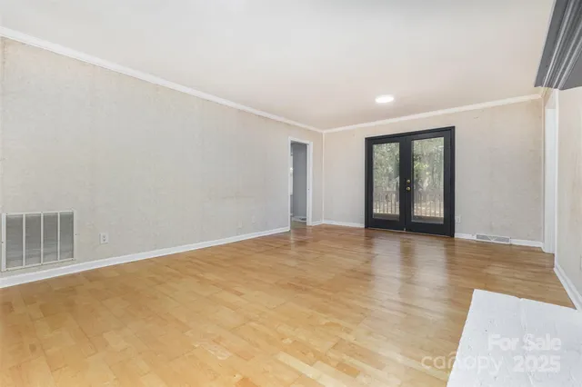 a view of an empty room with wooden floor and a fireplace