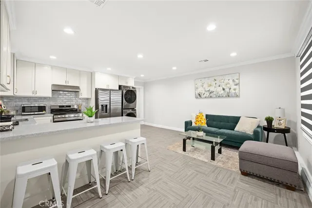 a living room with furniture a kitchen island with white cabinets and wooden floor