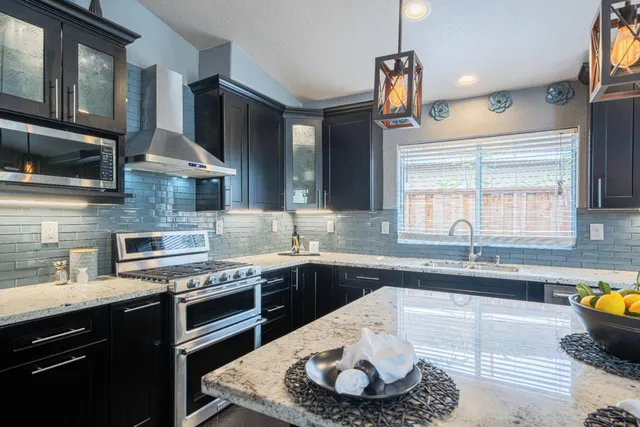 a kitchen with stainless steel appliances granite countertop a sink a stove and a wooden floors