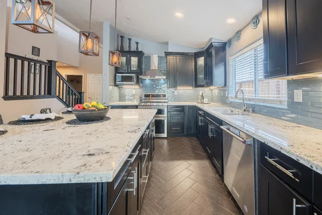 a kitchen with stainless steel appliances granite countertop a sink stove and refrigerator