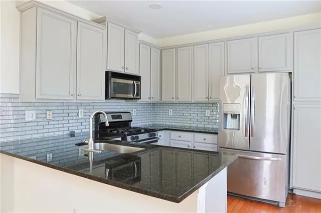 a kitchen with granite countertop a refrigerator a stove a microwave and cabinets