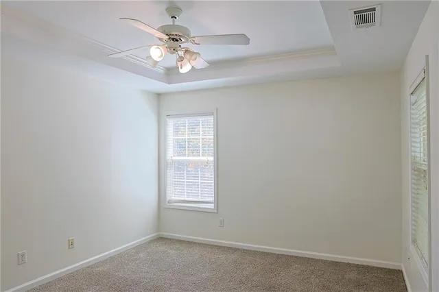 an empty room with windows and chandelier fan