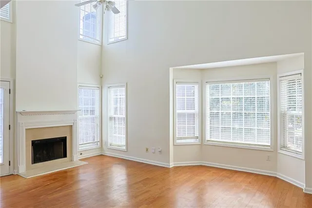 an empty room with wooden floor fireplace and windows