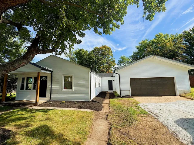 a view of a white house with a yard and potted plants