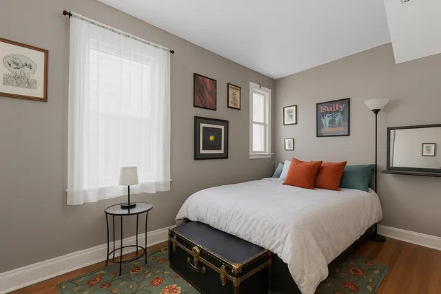 a bedroom with a bed a wall painting and a window