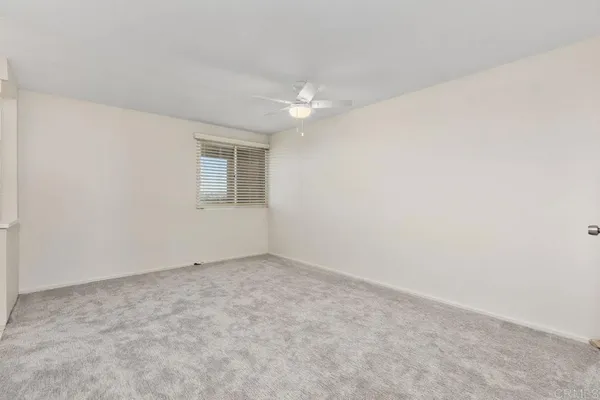 an empty room with chandelier fan and windows