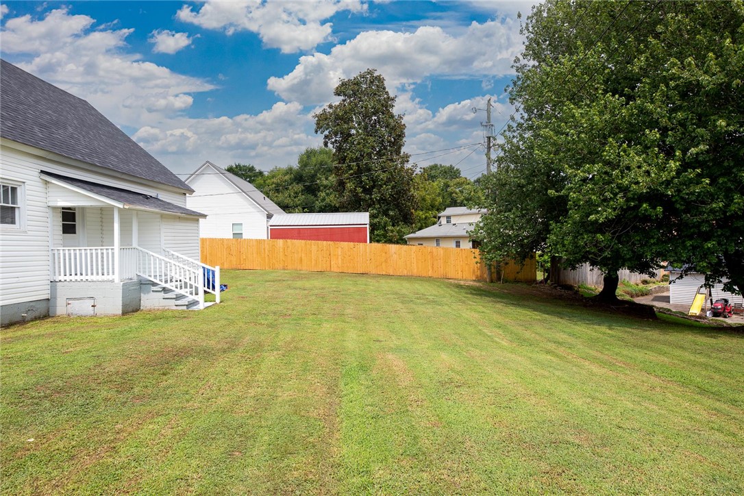 7 McCaughrin Street Pelzer, SC 29669 - Photo 23 of 24 A spacious backyard with mature trees offers ample room for outdoor activities, enclosed by a new privacy fence.