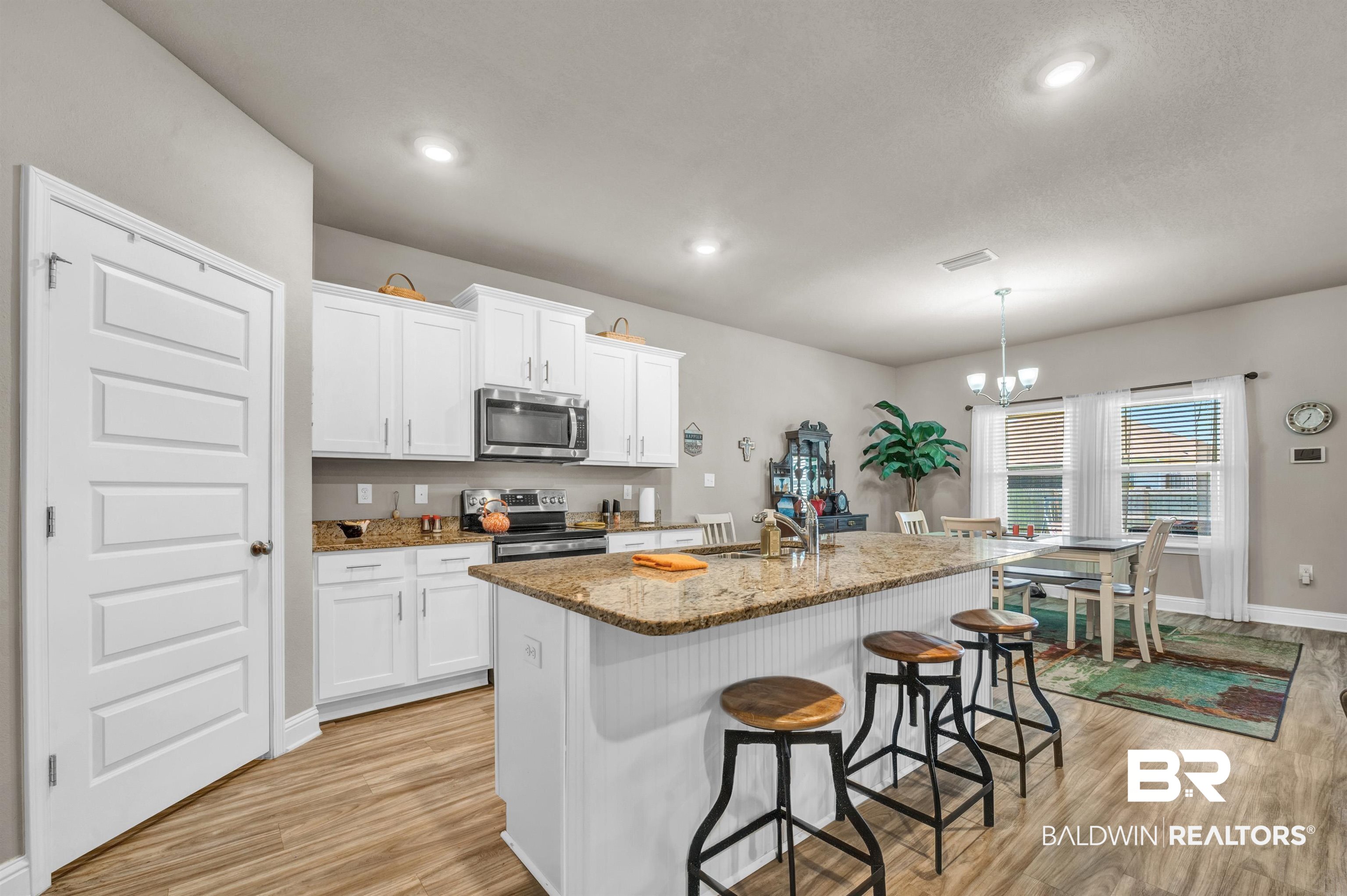 24655 Slater Mill Road Daphne, AL 36526 - Photo 12 of 36 Kitchen featuring stainless steel appliances, a sink, light wood-style floors, light stone countertops, and a kitchen bar