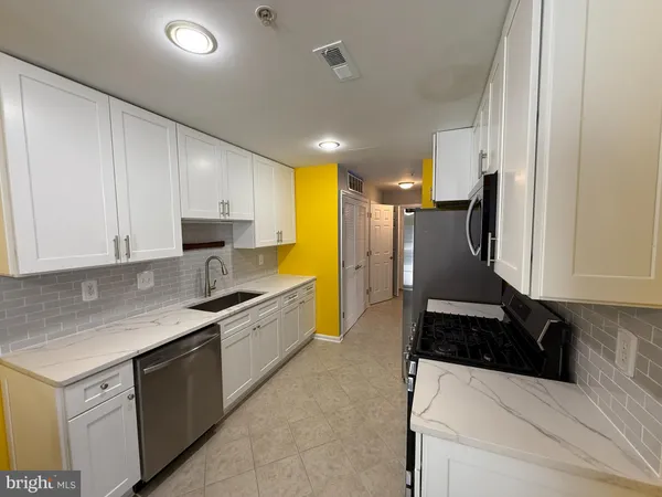 a kitchen with granite countertop a sink a stove and refrigerator