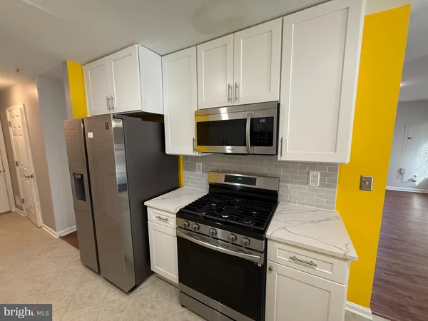 a kitchen with stainless steel appliances white cabinets and a stove top oven