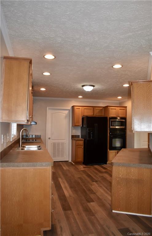 498 Ted Smith Road Rutherfordton, NC 28139 - Photo 11 of 38 a kitchen with stainless steel appliances kitchen island granite countertop a refrigerator a stove and a sink with wooden cabinets