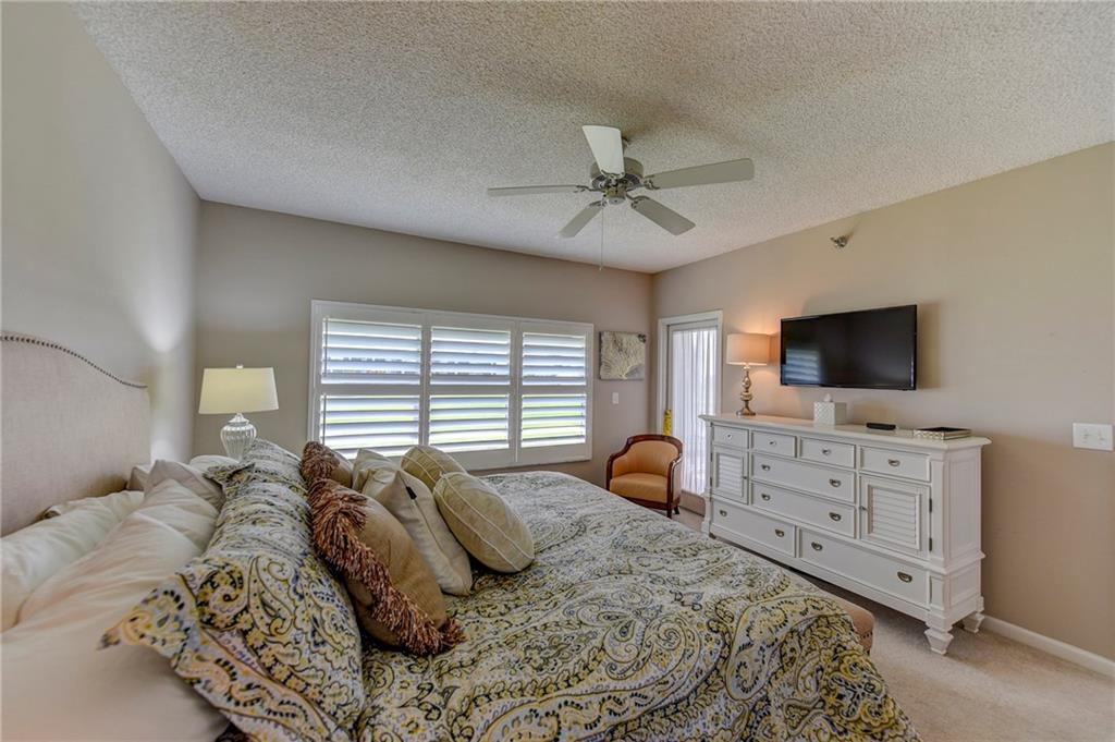 145 Northeast Edgewater Drive, Unit 4105 Stuart, FL 34996 - Photo 19 of 36 a bedroom with a bed and a flat screen tv