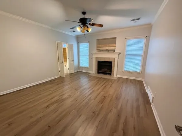 a view of an empty room with wooden floor fireplace and a window