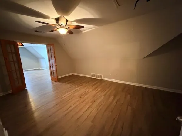 en empty room with wooden floor and fan