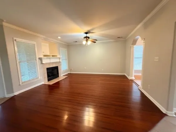 an empty room with wooden floor fireplace and windows