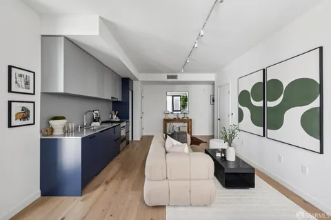 a living room with stainless steel appliances furniture and a wooden floor