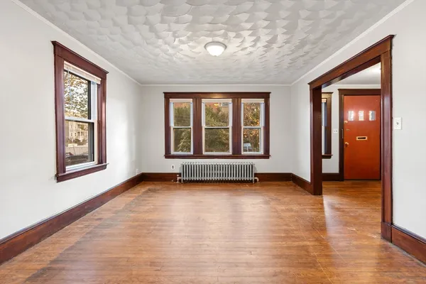 a view of an empty room with window and wooden floor