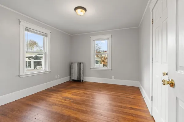 a view of an empty room with a window and wooden floor