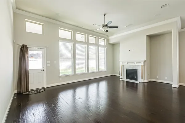an empty room with wooden floor fireplace and windows