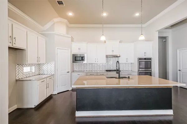 a view of a kitchen with kitchen island a sink stainless steel appliances and cabinets