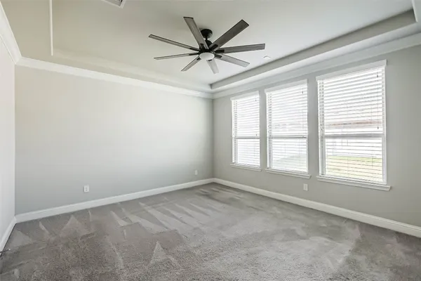 an empty room with a ceiling fan and windows