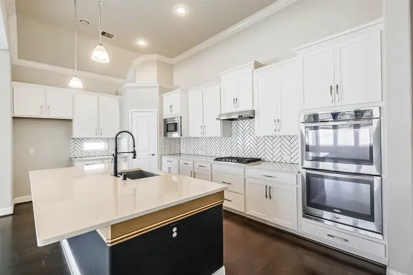 a kitchen with white cabinets appliances and a sink