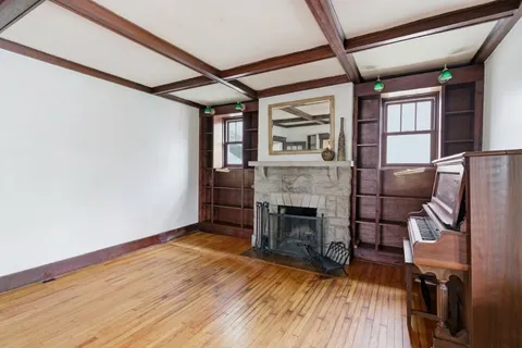a view of empty room with wooden floor and fireplace
