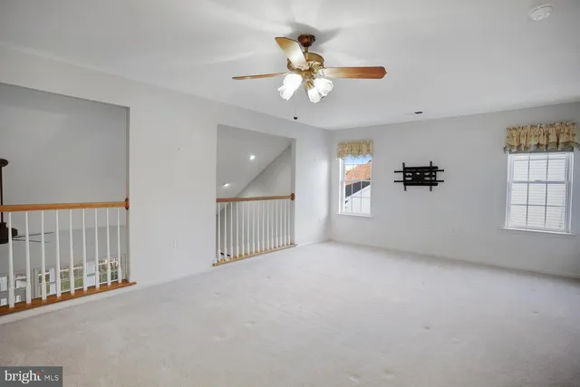 en empty room with windows and ceiling fan