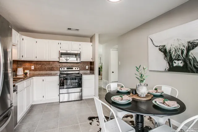 a kitchen with stainless steel appliances kitchen island granite countertop a sink a stove and white cabinets