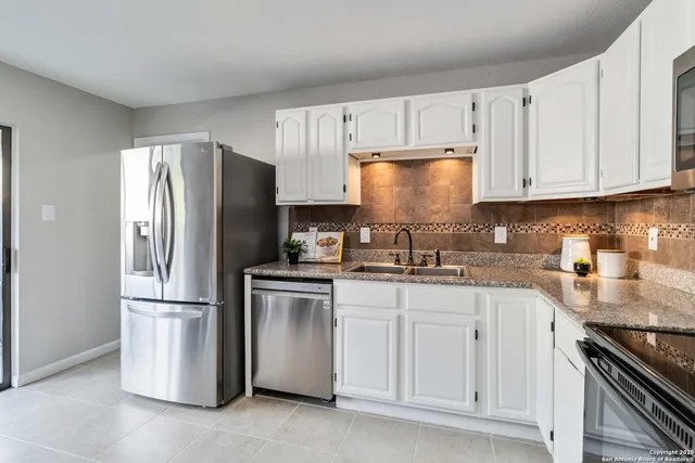 a kitchen with stainless steel appliances granite countertop a refrigerator a stove a sink and cabinets