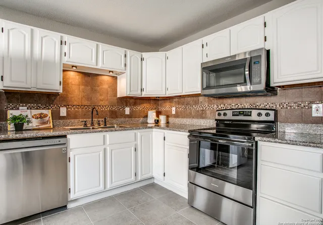 a kitchen with white cabinets stainless steel appliances and a sink