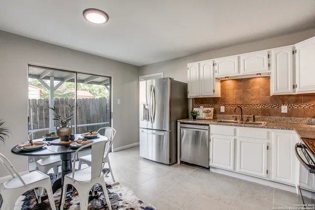 a kitchen with stainless steel appliances granite countertop a stove a refrigerator a sink dishwasher a dining table and chairs with wooden floor