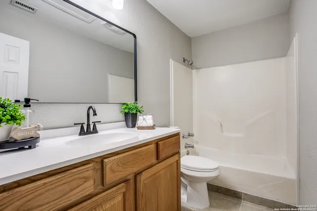 a bathroom with a granite countertop sink a toilet a mirror and shower