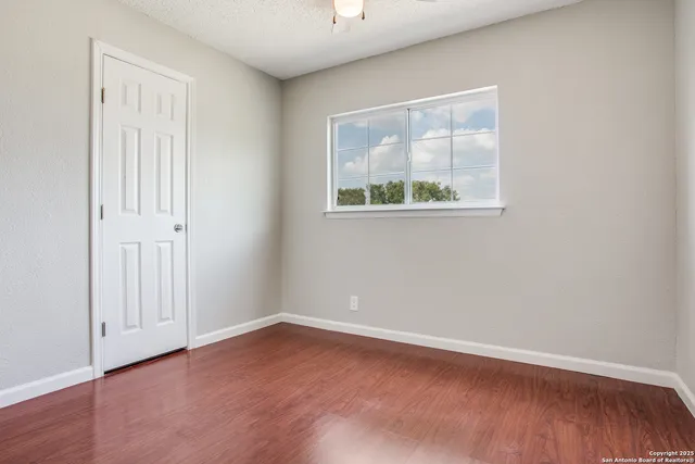 an empty room with wooden floor and window